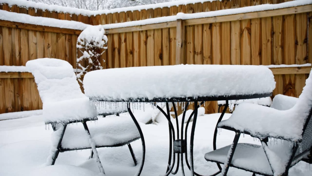 Tuinmeubelen bedekt met sneeuw in een wintertuin