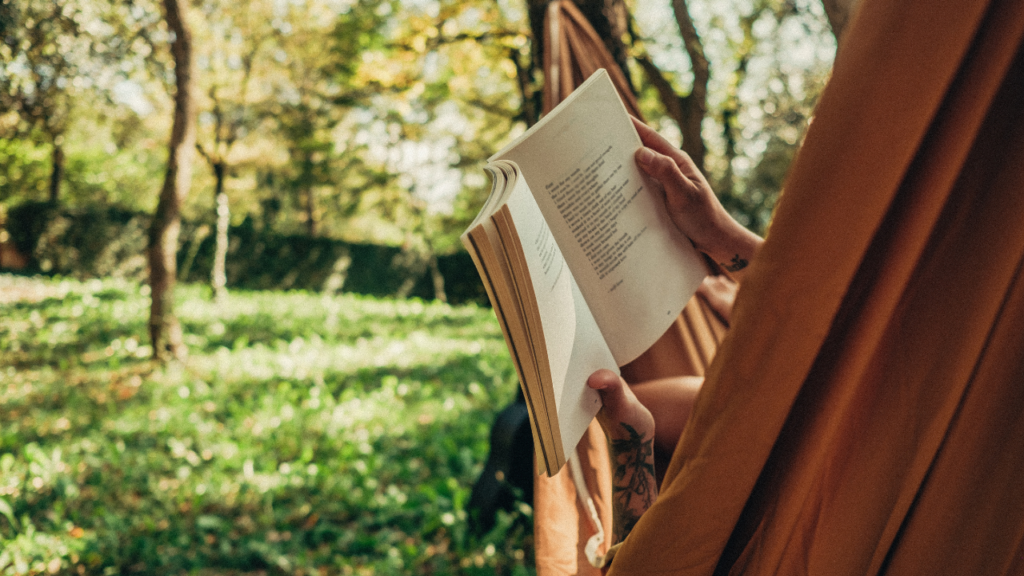 Persoon leest een boek in een hangmat in de tuin, omgeven door groene natuur, Boender Outdoor.