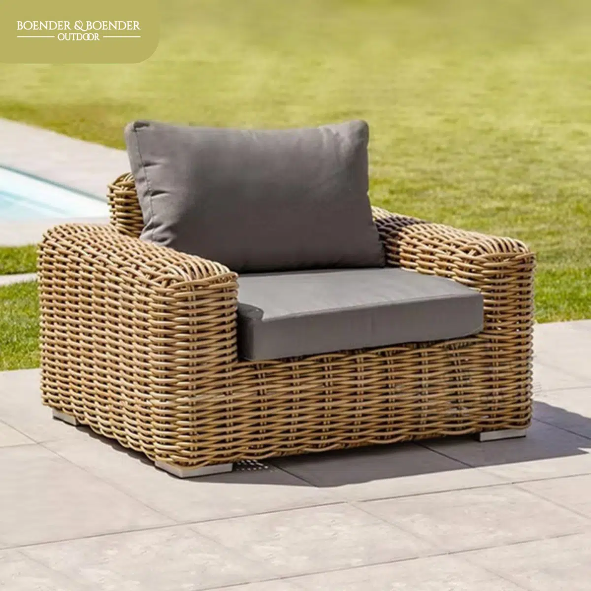 Rotan loungestoel met grijze kussens, ideaal voor gebruik in de tuin of op het terras.