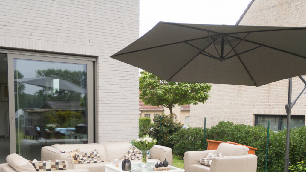 Moderne loungeset met beige kussens en grote parasol op een gezellig terras.