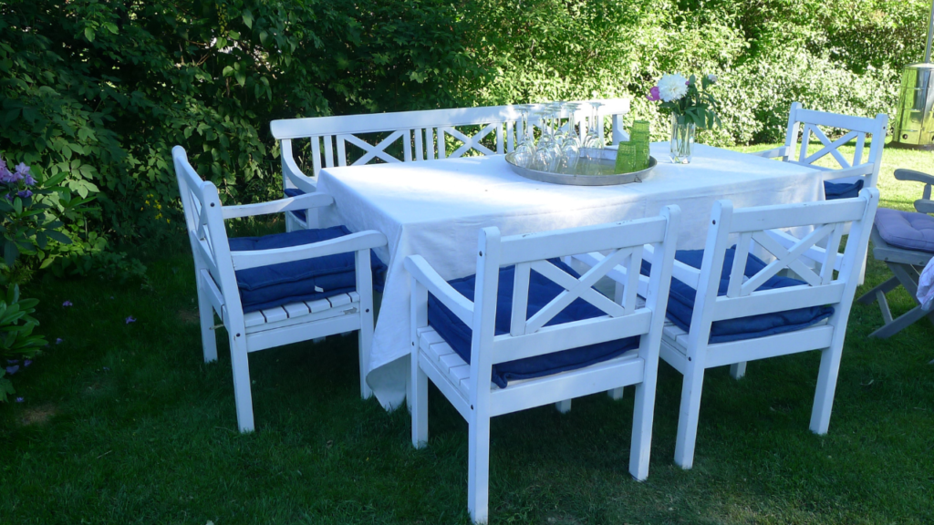 Witte aluminium tuinset met blauwe kussens op een groen gazon in zomertuin