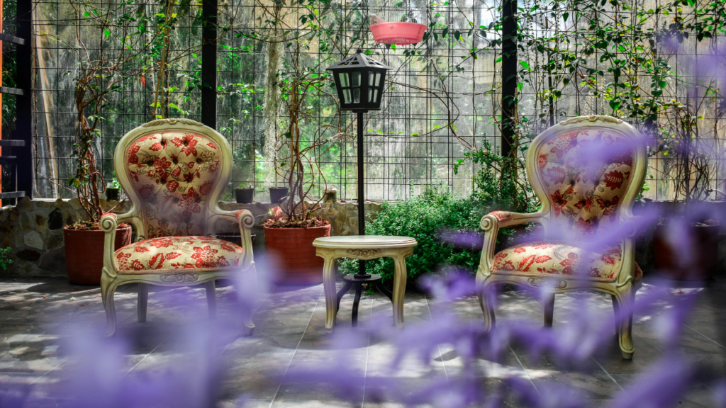 Vintage tuinstoelen met bloemenpatroon in een groene serre met lantaarn