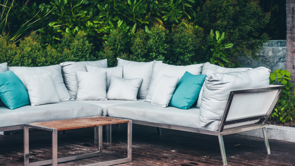 Moderne loungebank met blauwe sierkussens in groene tuin
