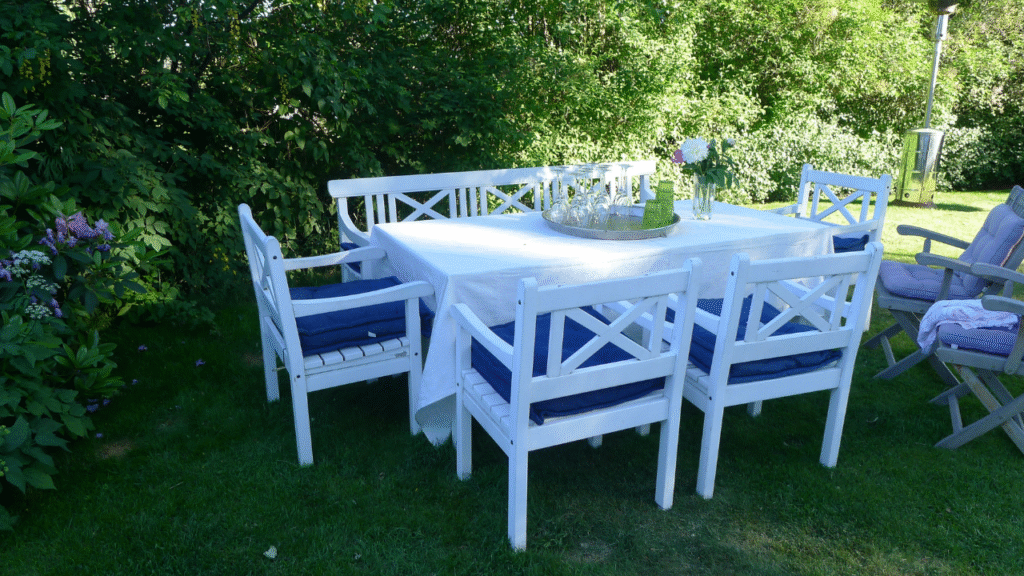 Witte tuinset met blauwe kussens in schaduwrijke tuin