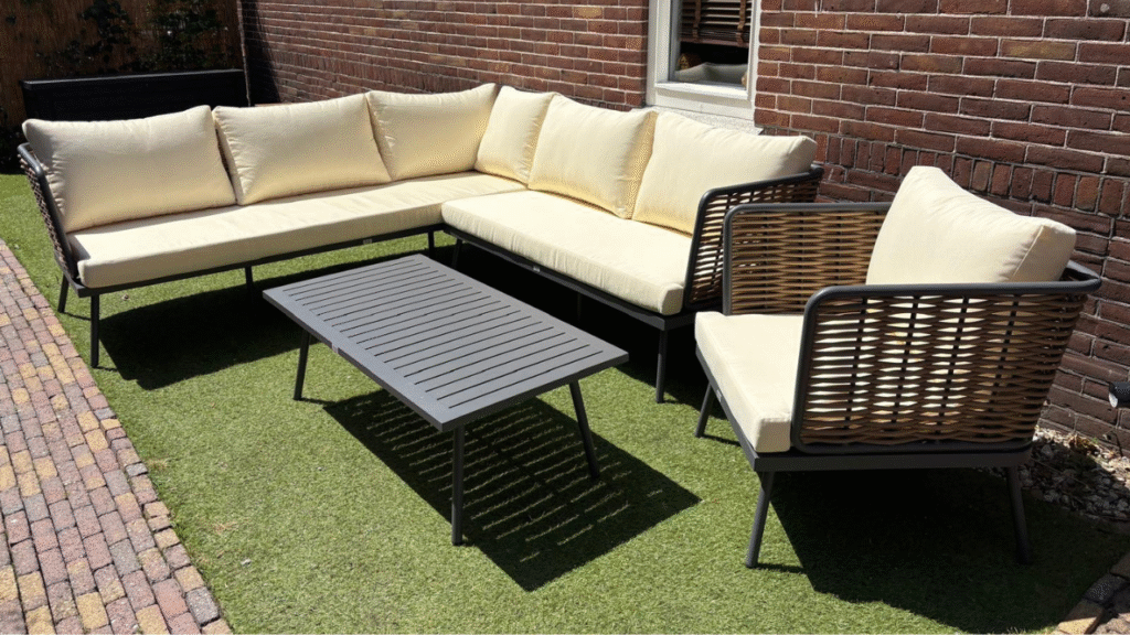 Moderne loungeset met beige kussens in een zonnige tuin op kunstgras