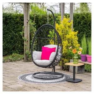Hangstoel in tuin met roze kussen en bijzettafel