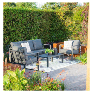 Tuinset met bank en stoelen op buitenkleed tussen groene hagen